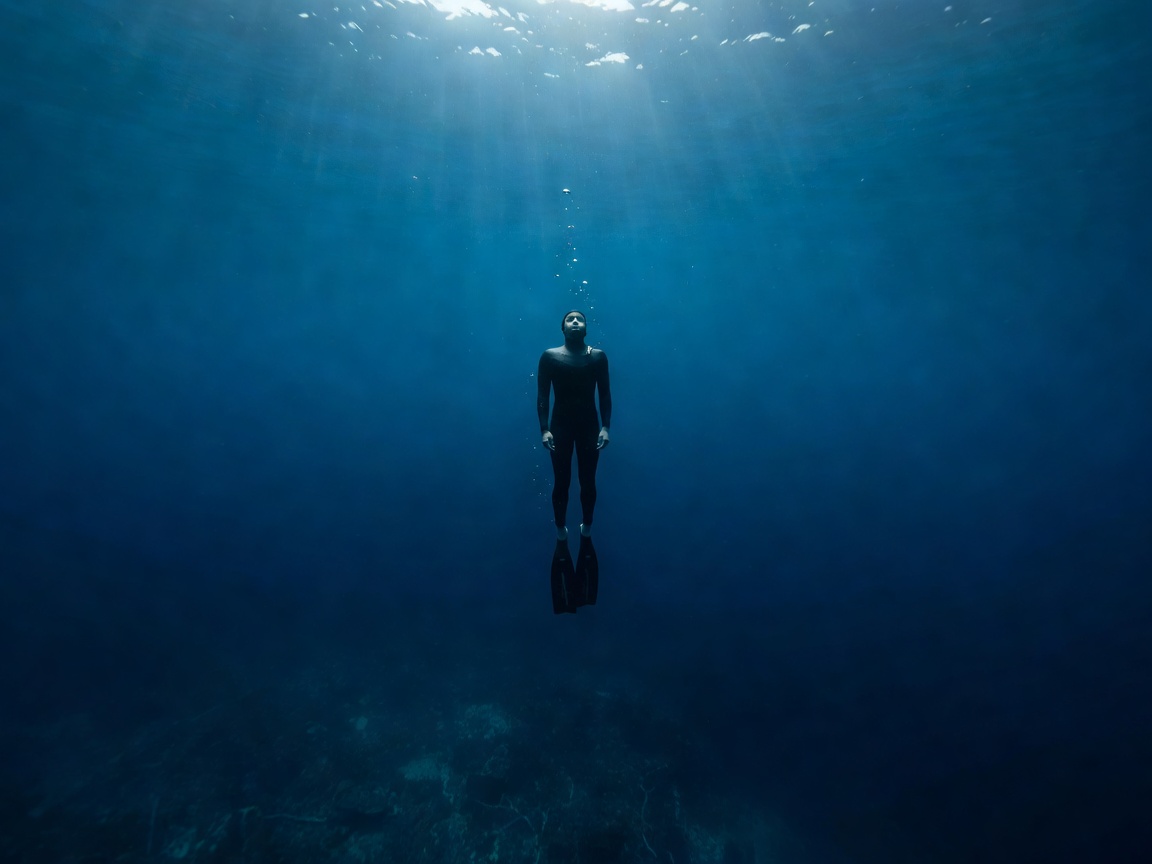 Freediver descending into the deep blue